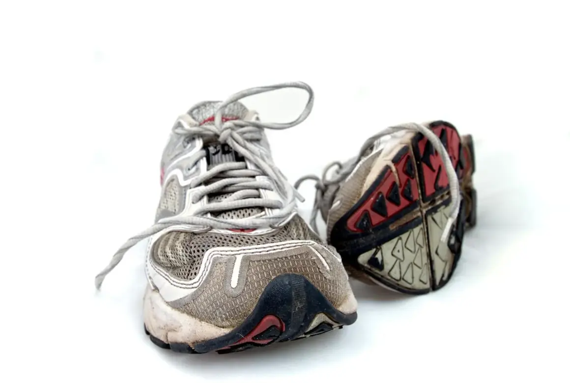 Abgenutzte Laufschuhe auf weißem Hintergrund. Die Sohlen zeigen Verschleiß, was Fragen aufwirft, wie lange halten laufschuhe wirklich?