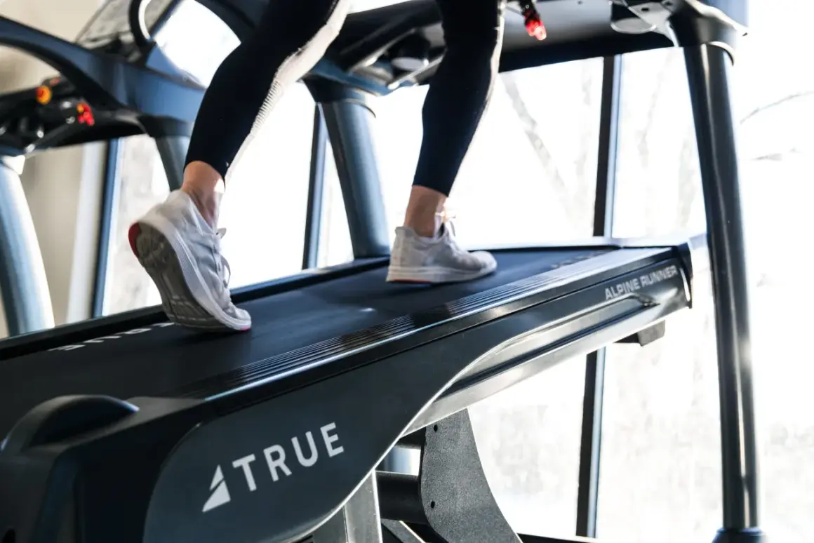 Beine trainieren auf einem Laufband mit Steigung. Das incline walking fordert die Muskulatur.