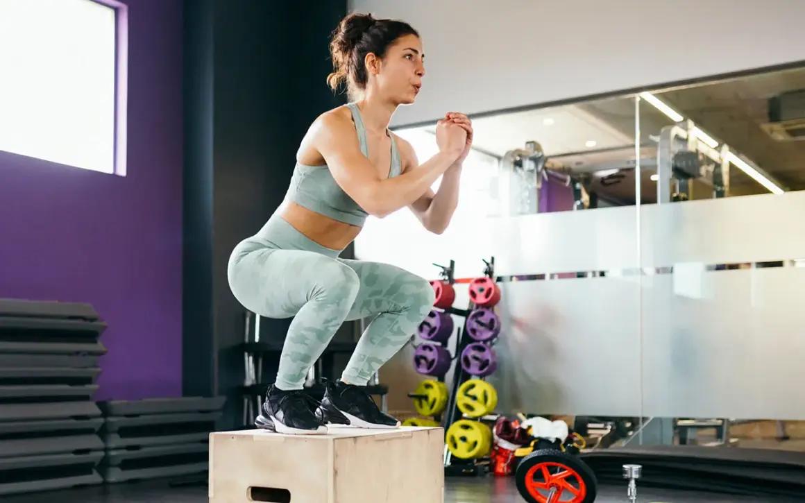 Frau macht einen Box Jump, eine Übung des plyometrischen Trainings, im Fitnessstudio.