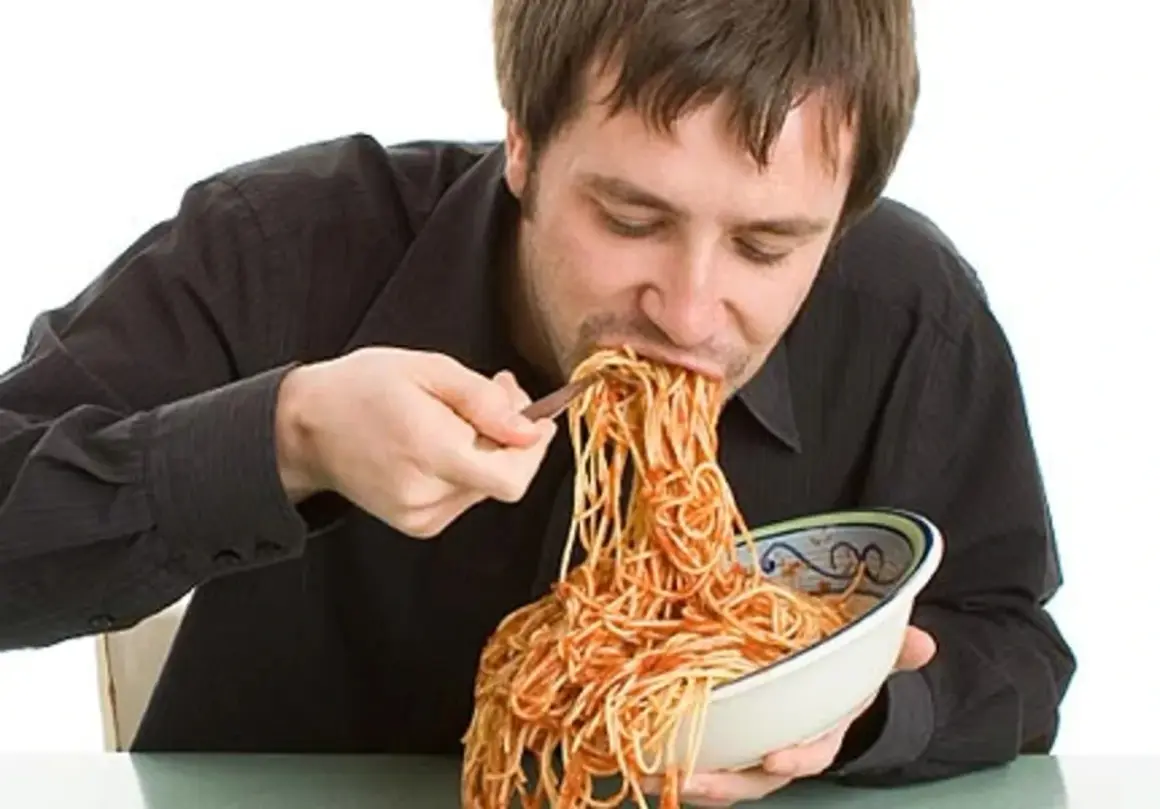 Mann isst genüsslich eine riesige Portion Spaghetti mit Tomatensoße. Perfekt für das Carb Loading vor dem Wettkampf!
