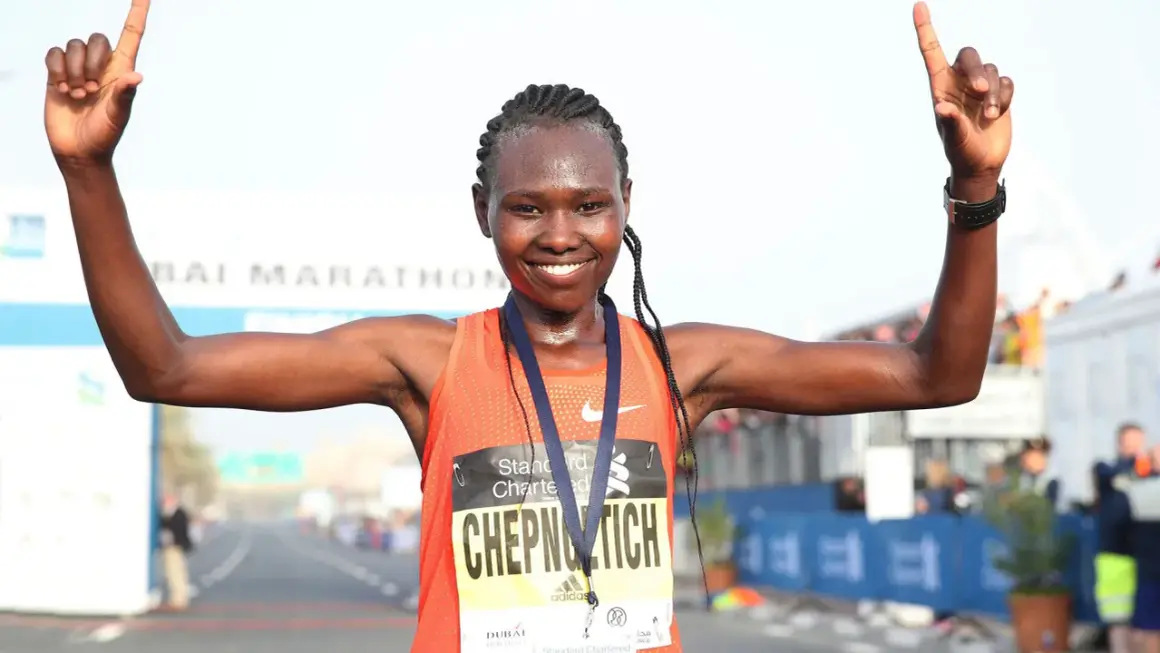 Ruth Chepngetich feiert ihren Sieg beim Dubai Marathon, die Arme erhoben und die Daumen nach oben.