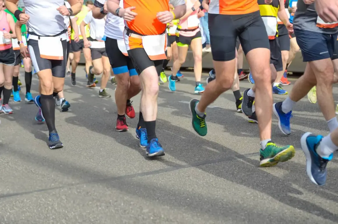 Läufer im Halbmarathon kämpfen um die beste Zeit. Bunte Laufschuhe und kurze Hosen dominieren das Bild.