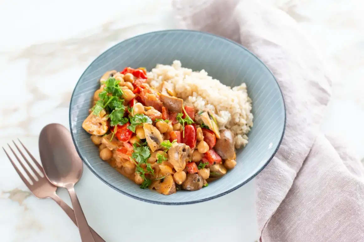 Ein köstliches, proteinreiches Abendessen: Kichererbsen-Curry mit Pilzen, Tomaten und Reis, garniert mit frischer Petersilie.