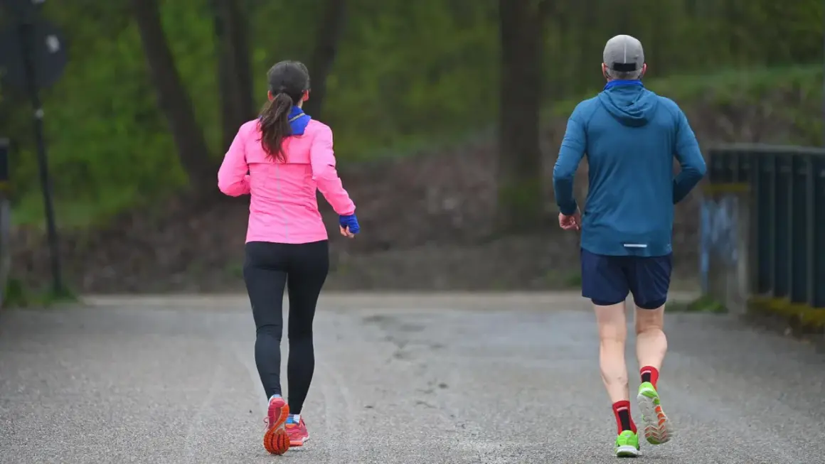 Zwei Läufer, eine Frau in Pink und ein Mann in Blau, genießen die frische Luft. Sie zeigen, was bringt joggen: Fitness und Wohlbefinden.