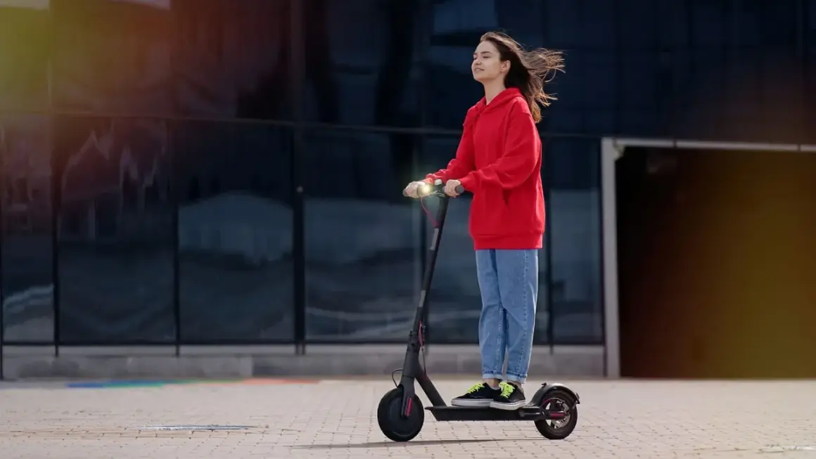 Junge Frau auf E-Scooter, genießt die Fahrt. Ab wann darf man E-Roller fahren? Ab 14 Jahren mit Zustimmung der Eltern.