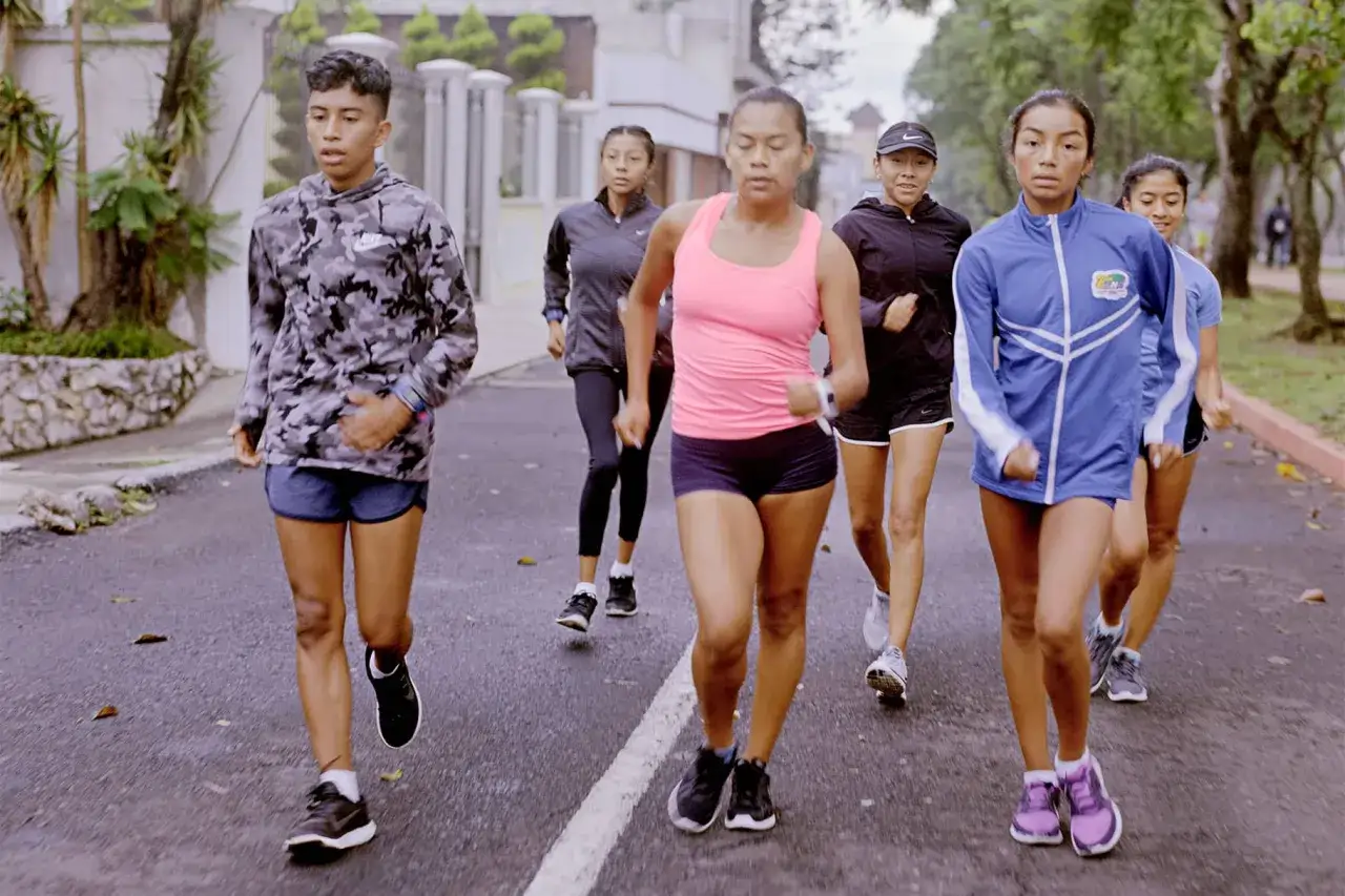 Eine Gruppe junger Athleten im power walking-Training auf einer Stra&szlig;e.