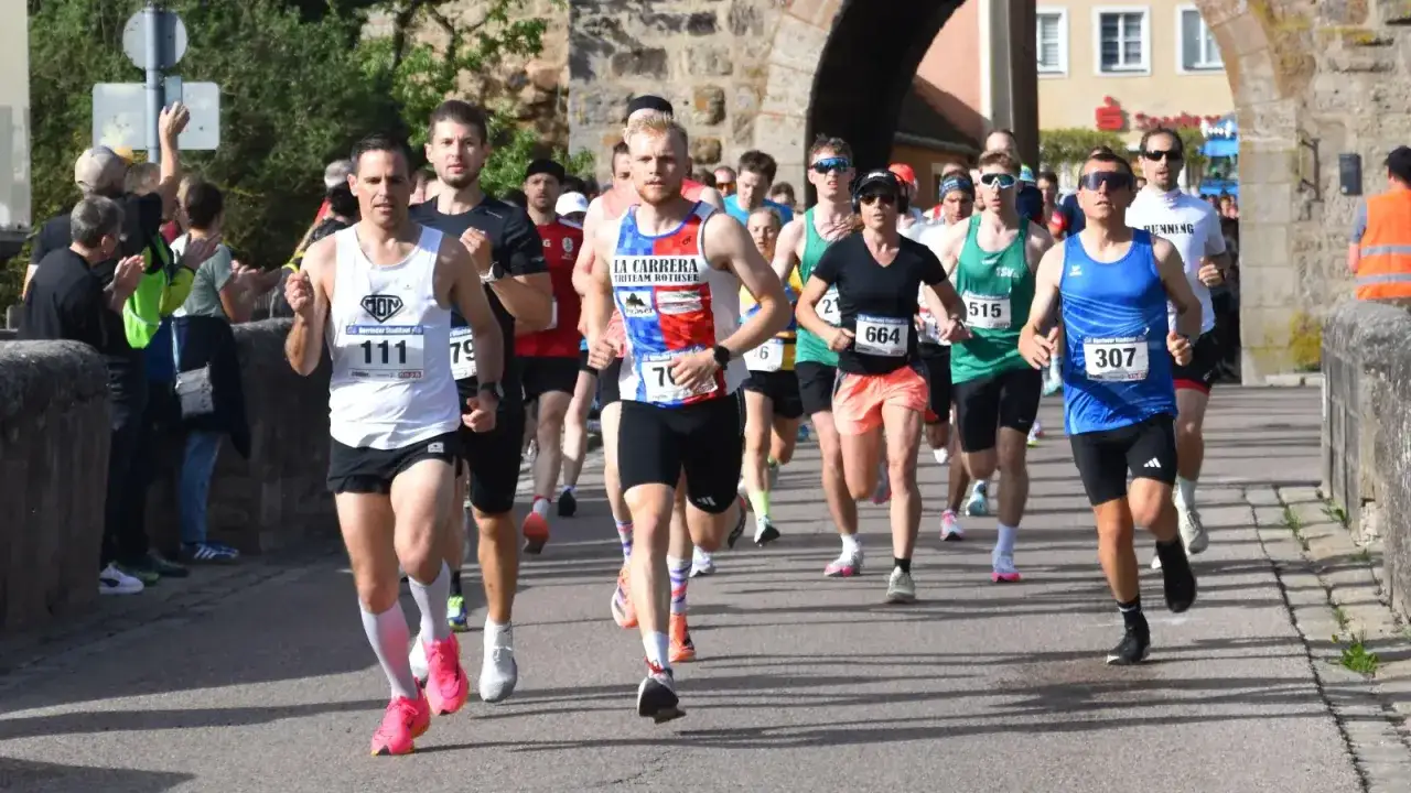 L&auml;ufer im Halbmarathon Deutschland k&auml;mpfen sich durch die Stadt. Nummer 111 f&uuml;hrt das Feld an, dicht gefolgt von anderen Teilnehmern.