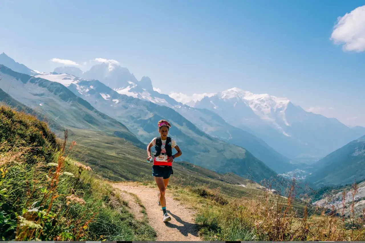 L&auml;uferin beim UTMB Mont Blanc Trailrunning-Wettkampf, umgeben von majest&auml;tischen Alpen.