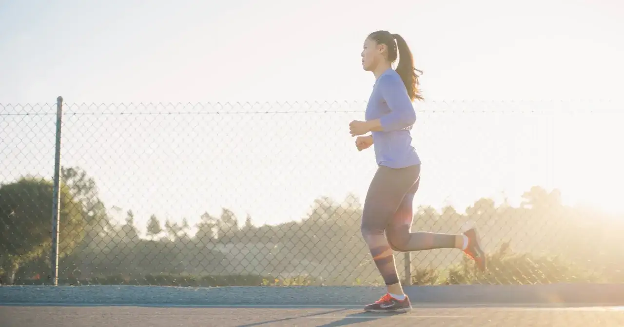 Frau joggt im Sonnenlicht, ein Zeichen f&uuml;r Fitness und Wohlbefinden nach der Geburt.