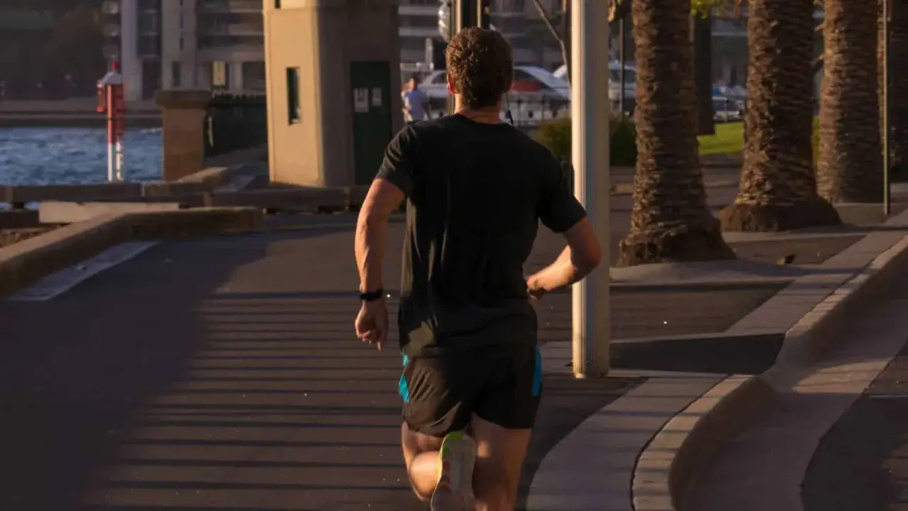 Mann joggt 3 km entlang der Promenade, vorbei an Palmen und dem Wasser.