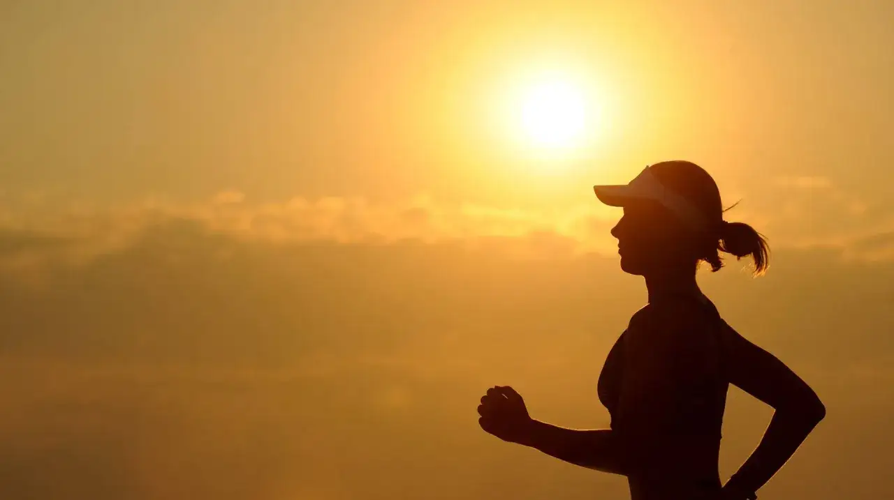 Silhouette einer L&auml;uferin im Sonnenuntergang. Sie genie&szlig;t die Freiheit und Energie, die das Joggen ihr bringt.