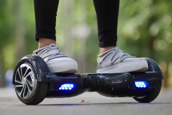 Person fährt Hoverboard mit leuchtenden blauen Lichtern. Die Frage "wie lange braucht ein Hoverboard zum laden?" beschäftigt viele Nutzer.