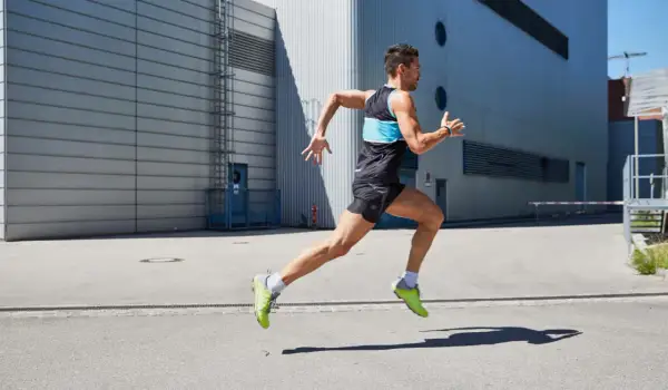 Ein Mann in Sportkleidung läuft dynamisch. Er konzentriert sich darauf, richtig laufen zu lernen, um seine Leistung zu verbessern.