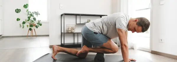 Mann massiert mit Foam Roller seinen vorderen Schienbeinmuskel, um Schmerzen zu lindern.