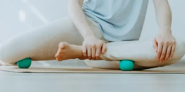 Person löst Verspannungen an den Beinen mit Bällen, um myofasziale Ketten zu lockern.