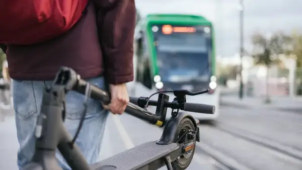 Person mit E-Scooter wartet auf die S-Bahn.