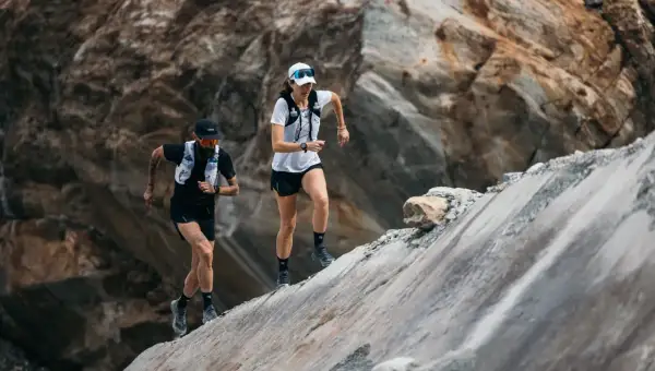 Zwei Läufer meistern einen steilen, felsigen Hang. Sie sind Teil eines Ultramarathons, einer extremen Laufdisziplin.